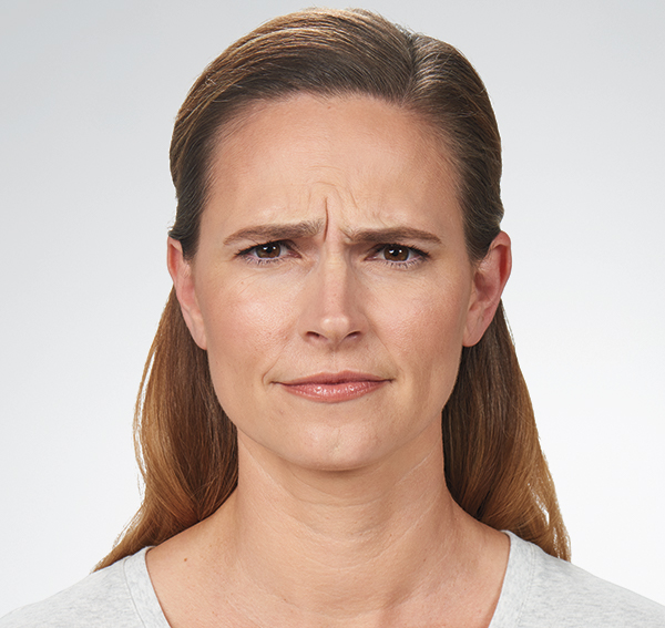 Woman with frown lines and a concerned expression, highlighting the effects of aging on skin, related to Botox treatment for frown lines and facial rejuvenation.